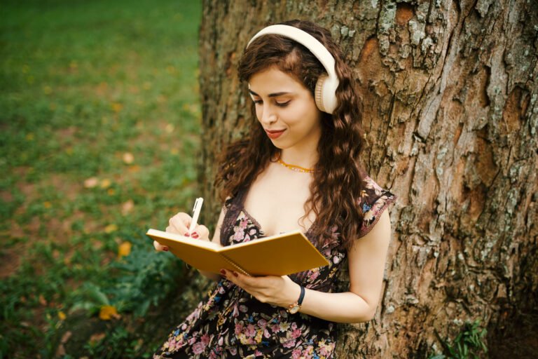 Girl making notes in diary under tree
