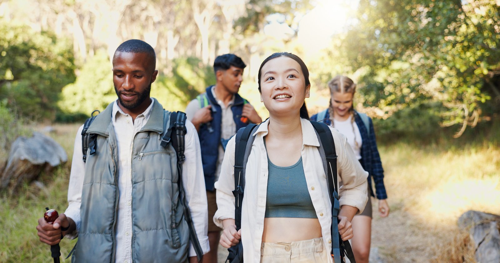 Group, friends and hiking in forest for backpacking, travel adventure and fitness in environment. People, walk and trekking journey to explore woods, nature survival or sightseeing for exercise hobby