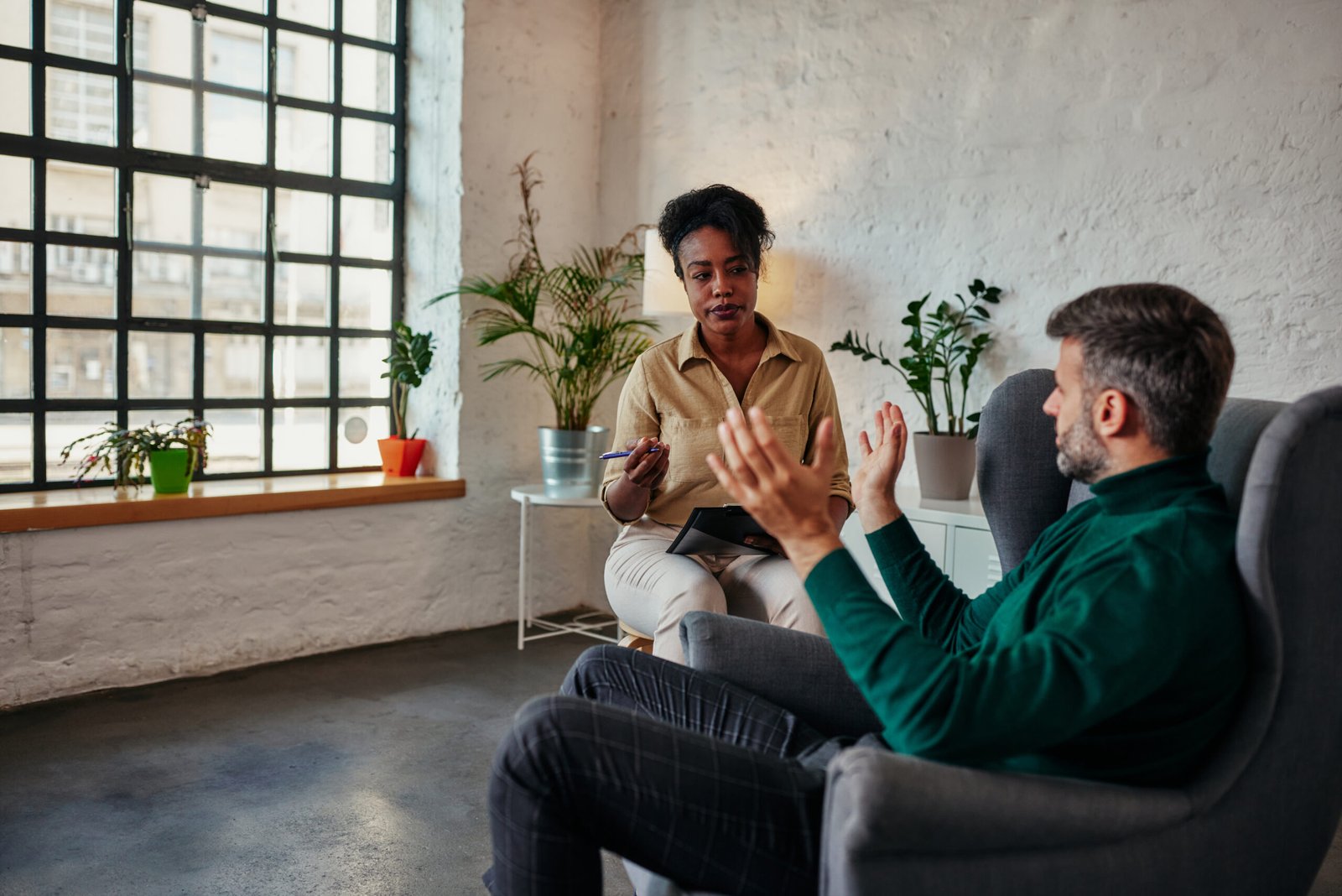 African female therapist listens to mid adult male client