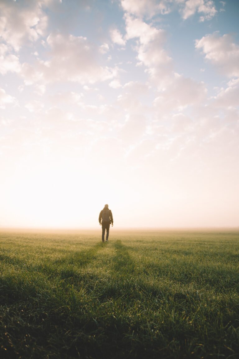 Man Walking On Field Against Sky During Sunset