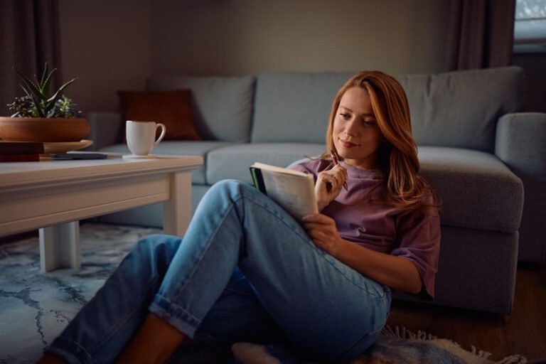 Smiling woman writing in diary while relaxing at home.