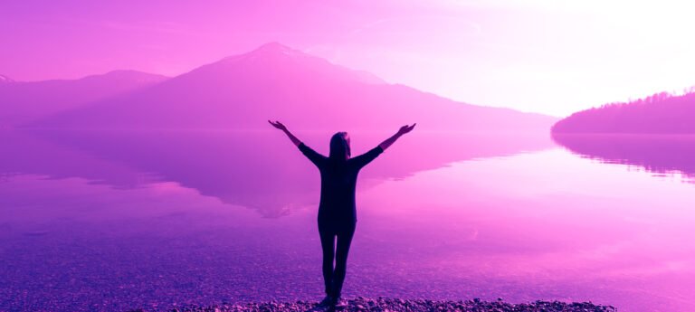 Female figure with wide open arms. Fantastic nature mountain peaks reflected in the water of the lake. The bright light of the sun.