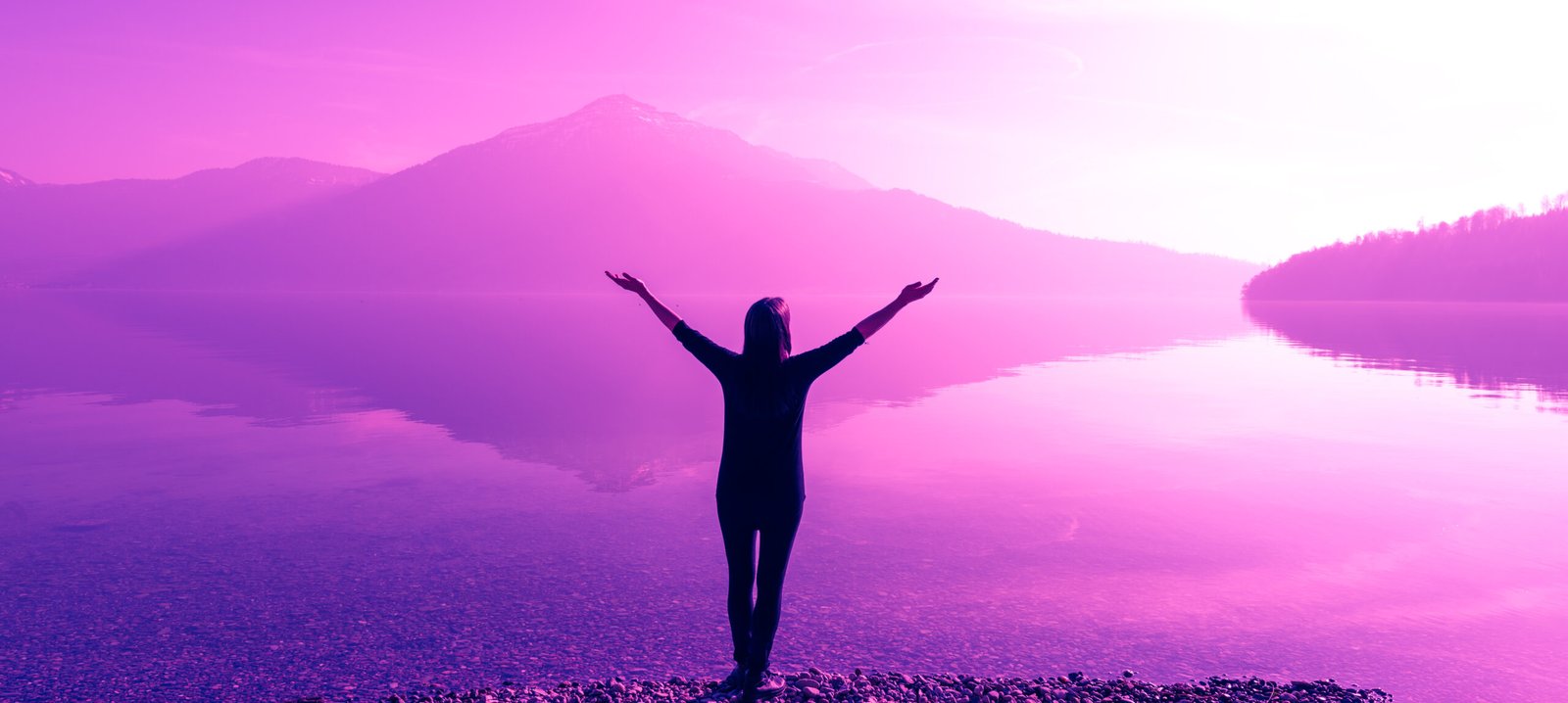 Female figure with wide open arms. Fantastic nature mountain peaks reflected in the water of the lake. The bright light of the sun.