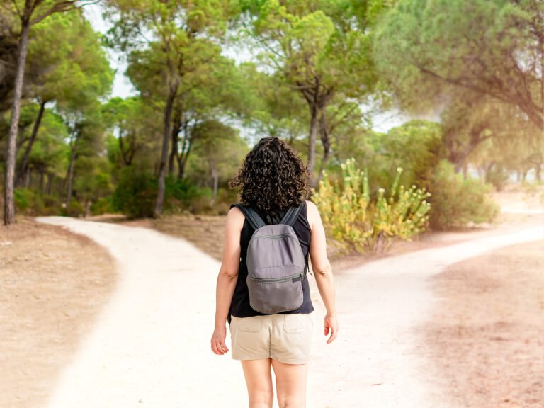 Woman choosing to take a light path or a dark path in a forest. Concept of decision making in life.