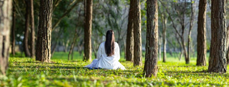 Woman relaxingly practicing meditation in the pine forest to attain happiness from inner peace wisdom with beam of sun light for healthy mind and soul for healthy mind and soul