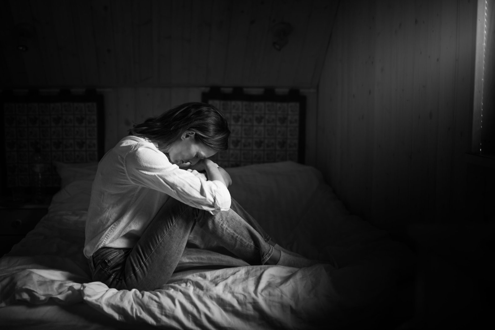 Lonely tired stressed woman alone in a dark room. People fear, sadness, abuse, depression, addiction.