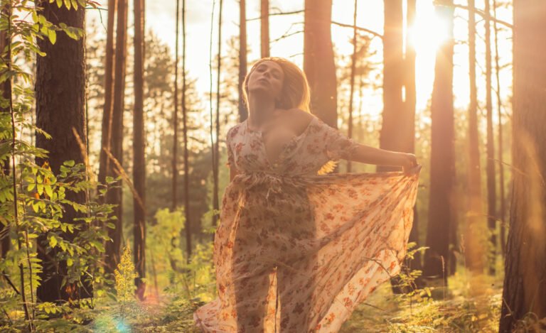 Portrait of young beautiful girl in summer dress in forest that dancing