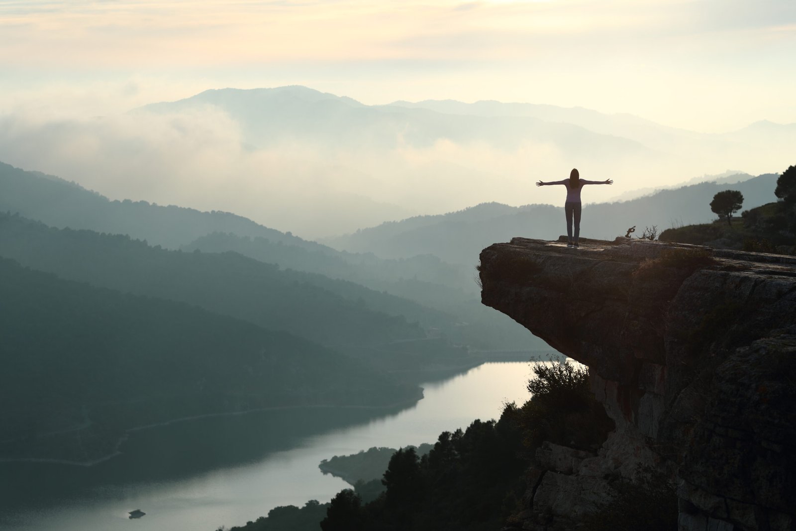 Woman outstretching arms in a cliff contemplating nature