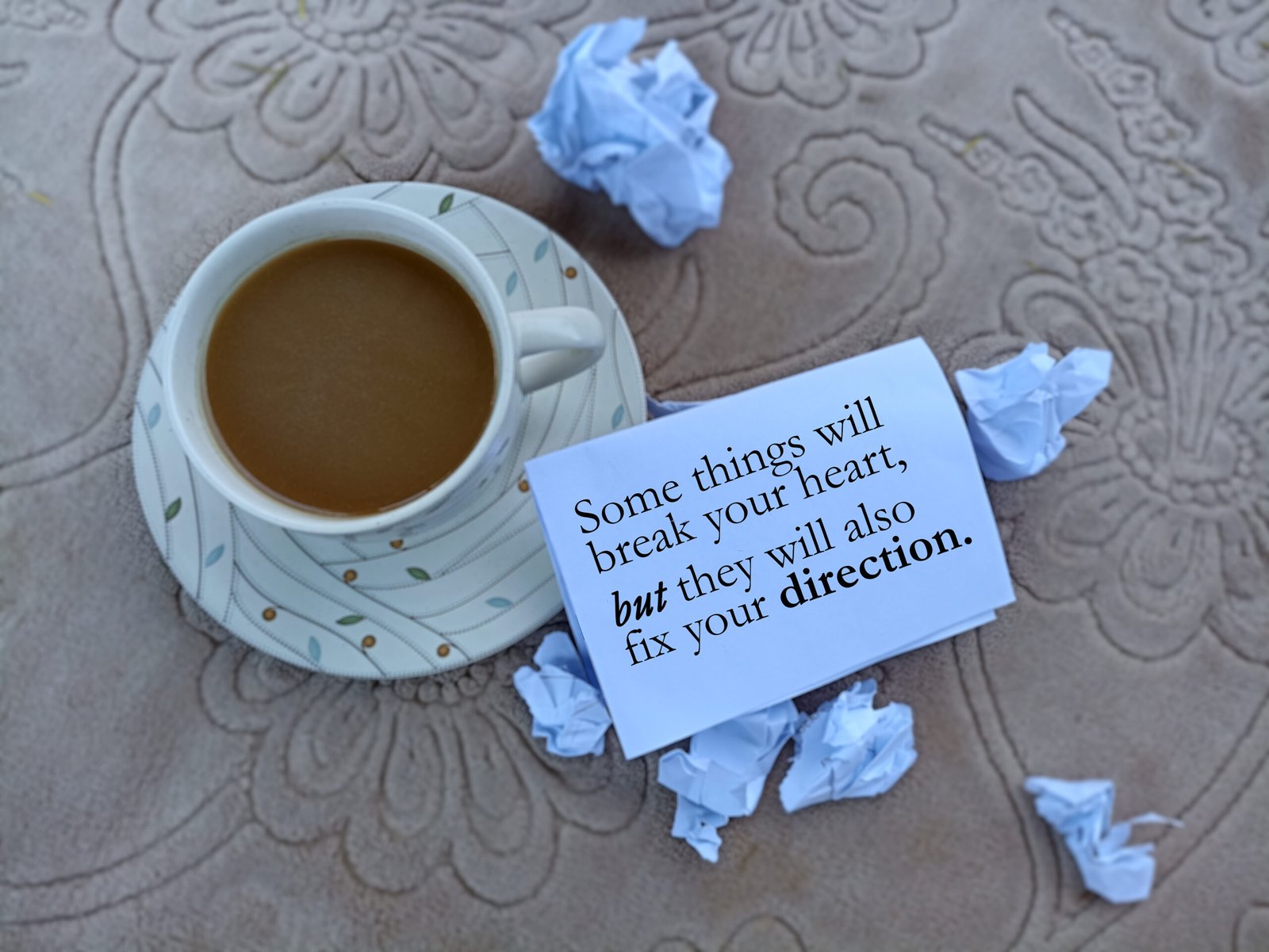 Cup of coffee positive text message on a paper - Some things will break your heart, but they will also fix your direction.