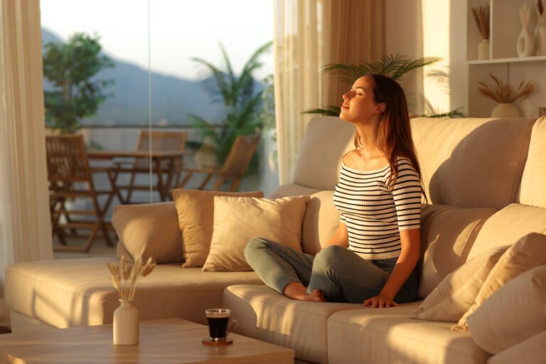 Casual woman breathing fresh air on a couch at sunset