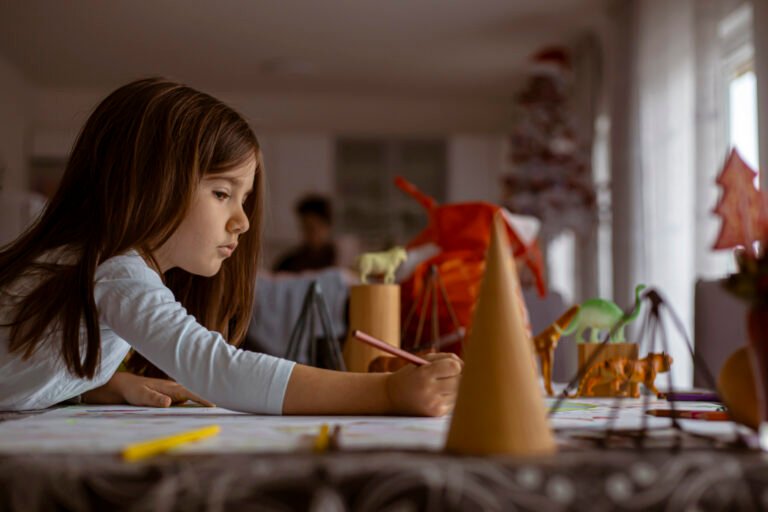 iStock photo of a girl drawing and playing with plastic toy animals and geometric figures