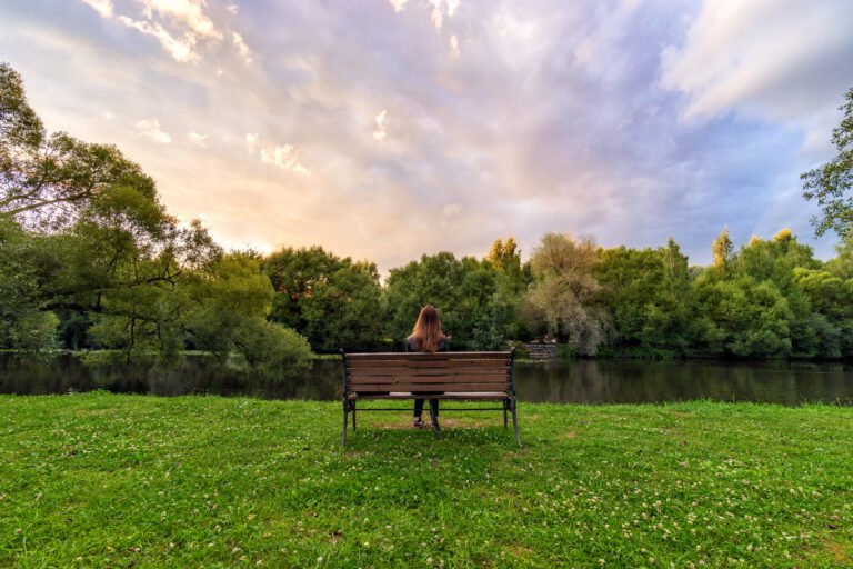 A Young Woman Sitting Alone On A Bench In Green Park