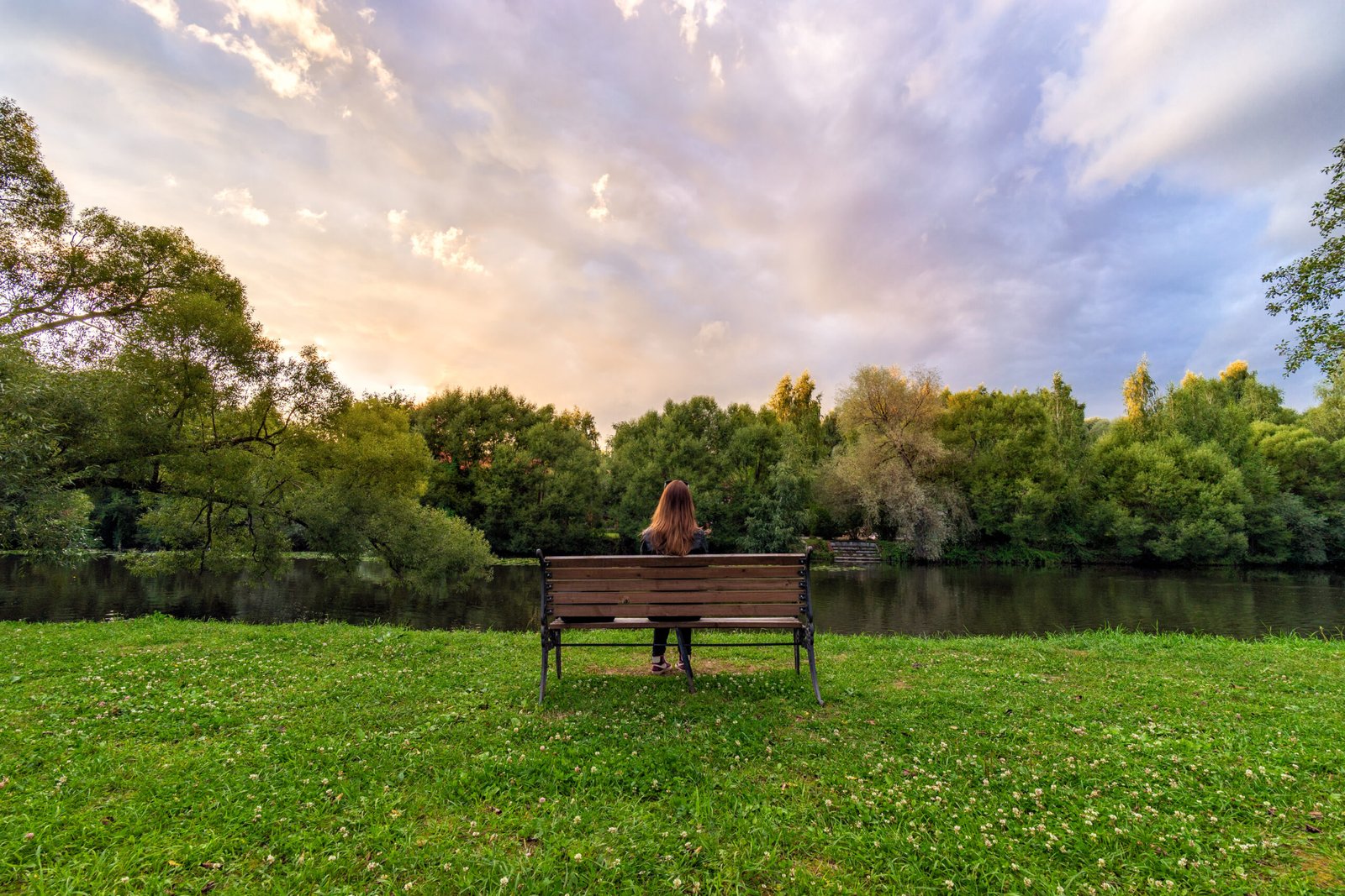 A Young Woman Sitting Alone On A Bench In Green Park