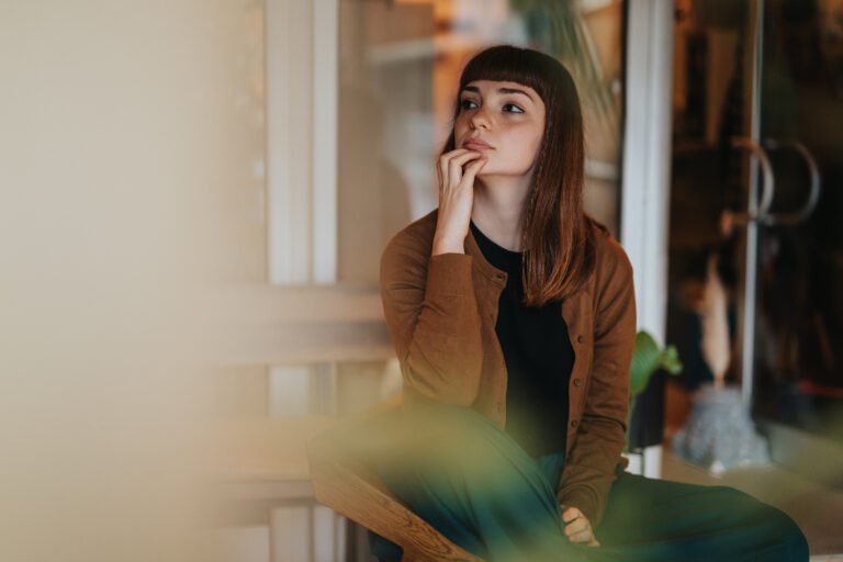 Thoughtful young woman sitting indoors in a cozy atmosphere