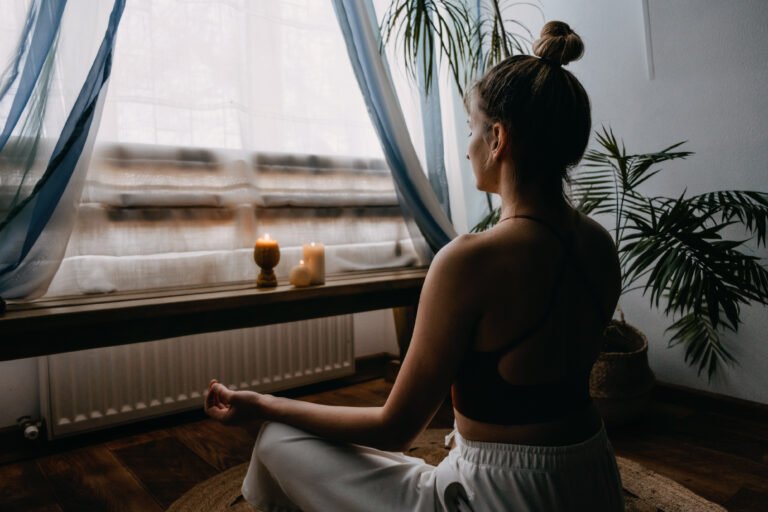 Self-care, self-compassion, mental wellbeing in post-pandemic world. Mental health, wellbeing, meditation to eliminate anxiety. Young woman sitting on floor do yoga exercise and meditation at home
