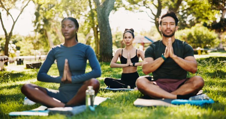 Meditation, prayer hands and group in park for mindfulness, healing aura or spiritual mental health. Zen, yoga people and peaceful in nature with fresh air, energy balance or relax chakra outdoors