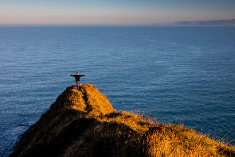 Person with a sense of freedom on a cliff with a panoramic view of the open sea