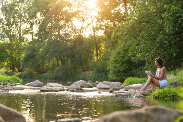 Landscape with a woman reading near the river in the middle of the nature