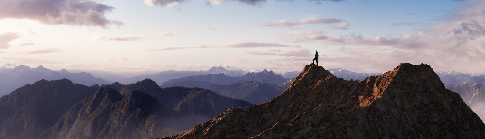 Adventurous Man Hiker Standing on top of a rocky mountain overlooking the dramatic landscape