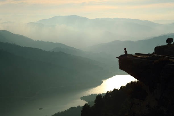 Silhouette of a woman sitting and contemplating nature in a cliff