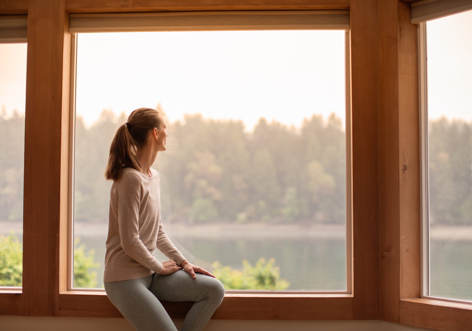 Young woman looking out a window feeling calm and at peace.