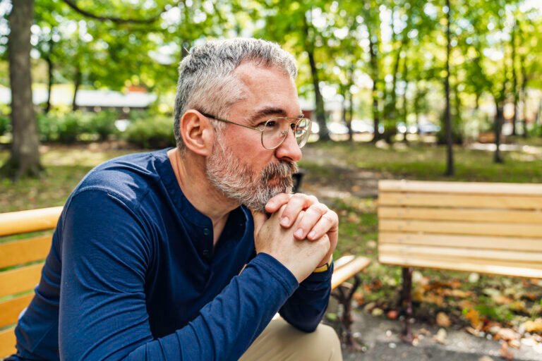 Portrait of a mature man sitting on a bench in an urban park