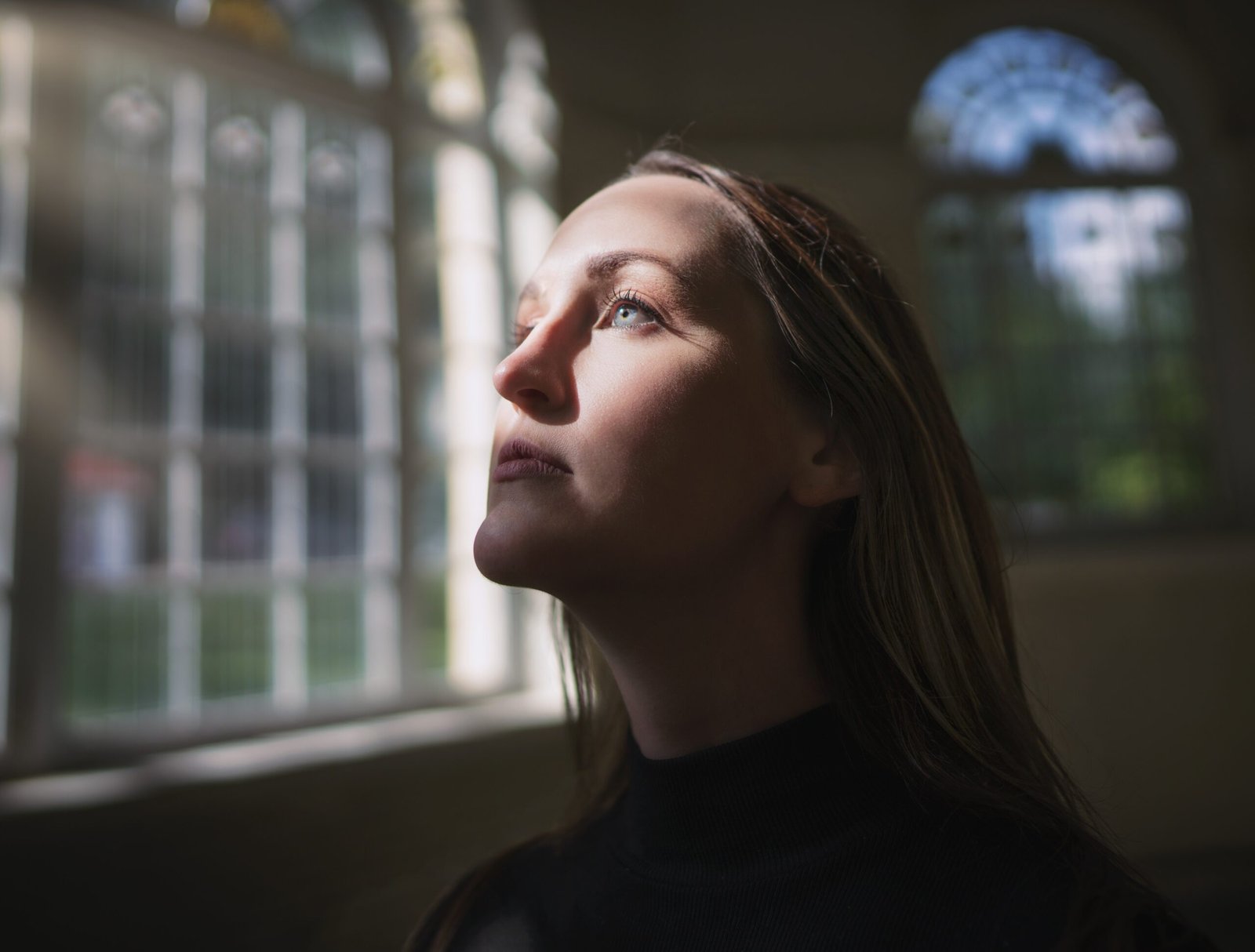 caucasian woman looking through window with face illuminated