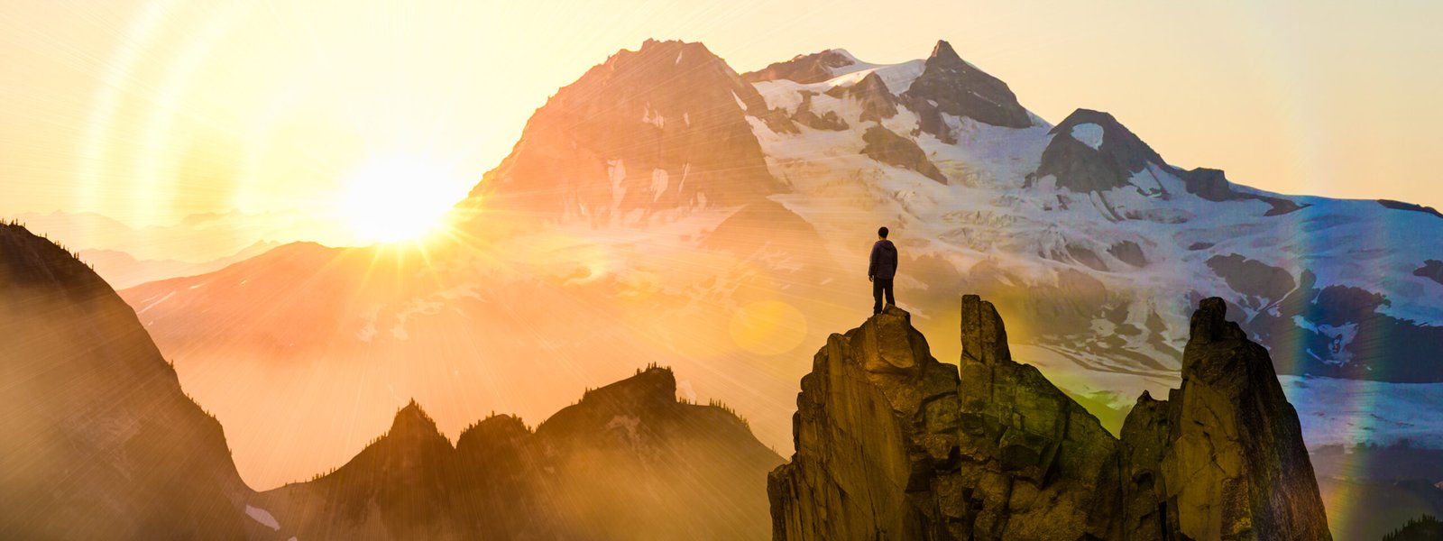 Man standing on mountain peak at sunrise looking at peaks, success motivation goal achievement freedom adventure strength victory inspiration, breathtaking scenery high altitude