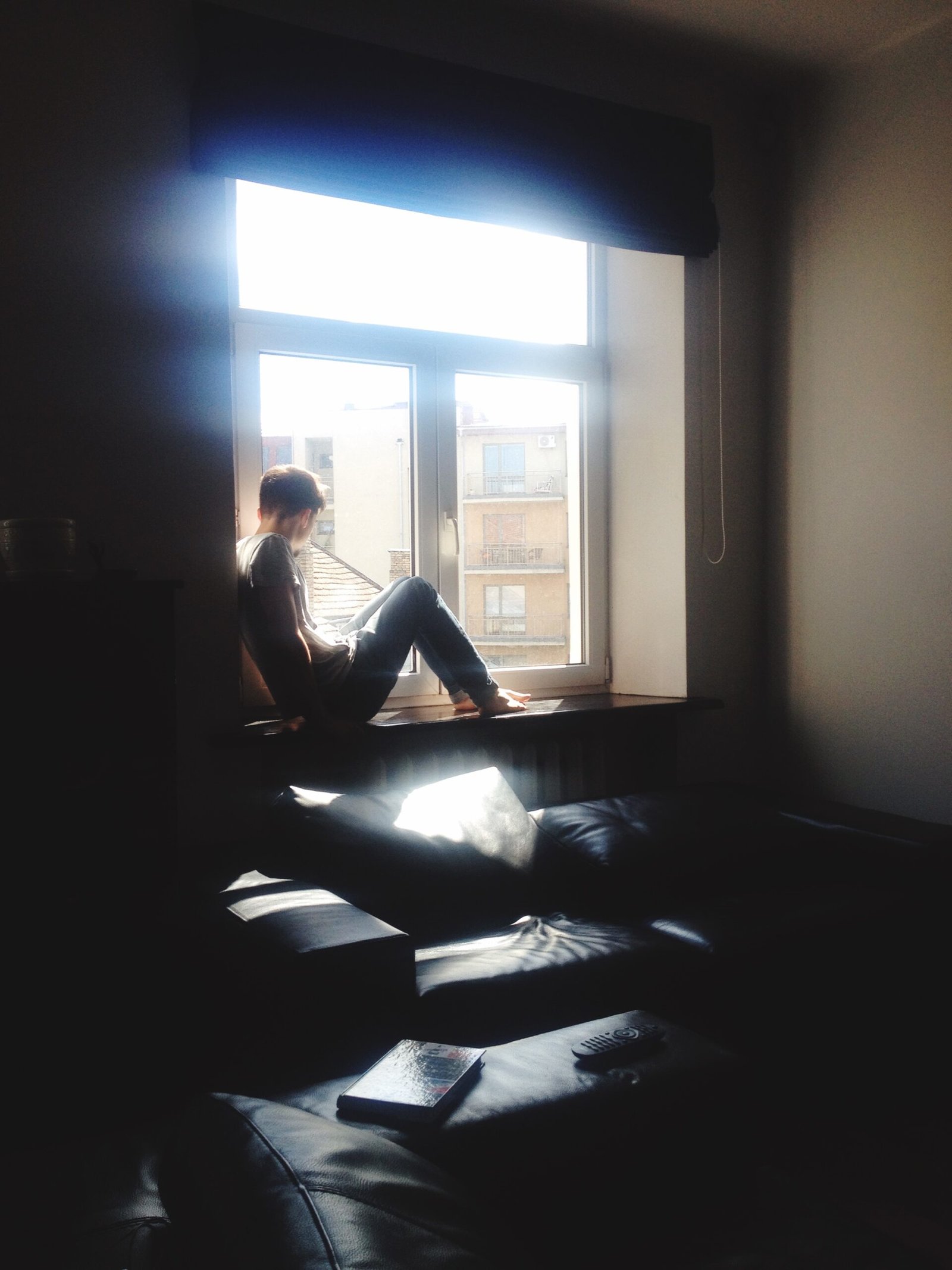 Man Sitting On Window Sill At Home