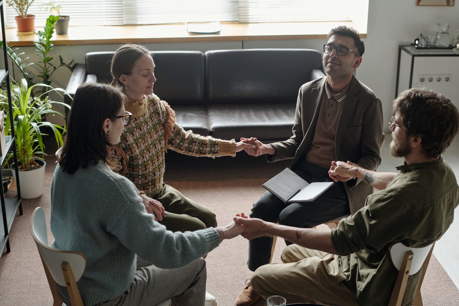 Diverse Young Adults Participating in Group Therapy Session Holding Hands