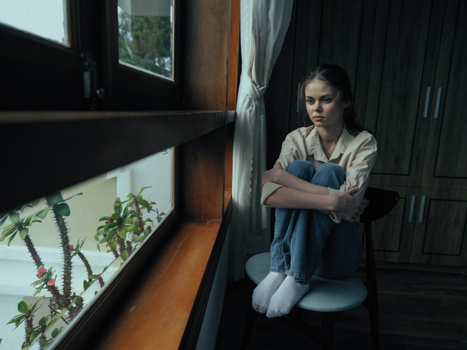 Woman fall depression sitting by the window and looking at nature, rainy weather and discouragement, home life style, loneliness.