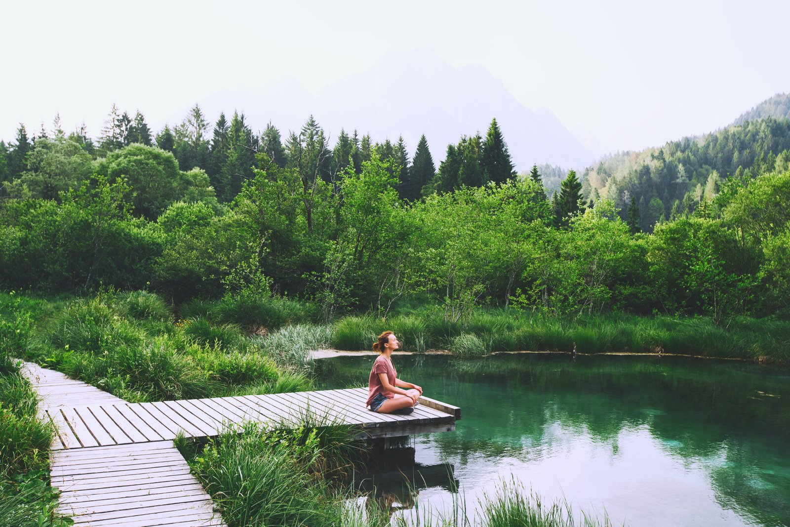 Young woman doing yoga and meditating in lotus position on the background of nature.