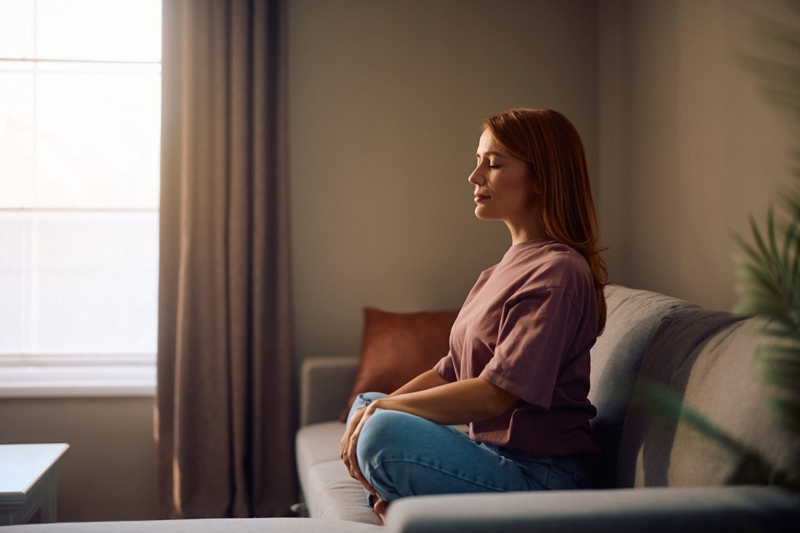 Calm woman meditating in the living room.