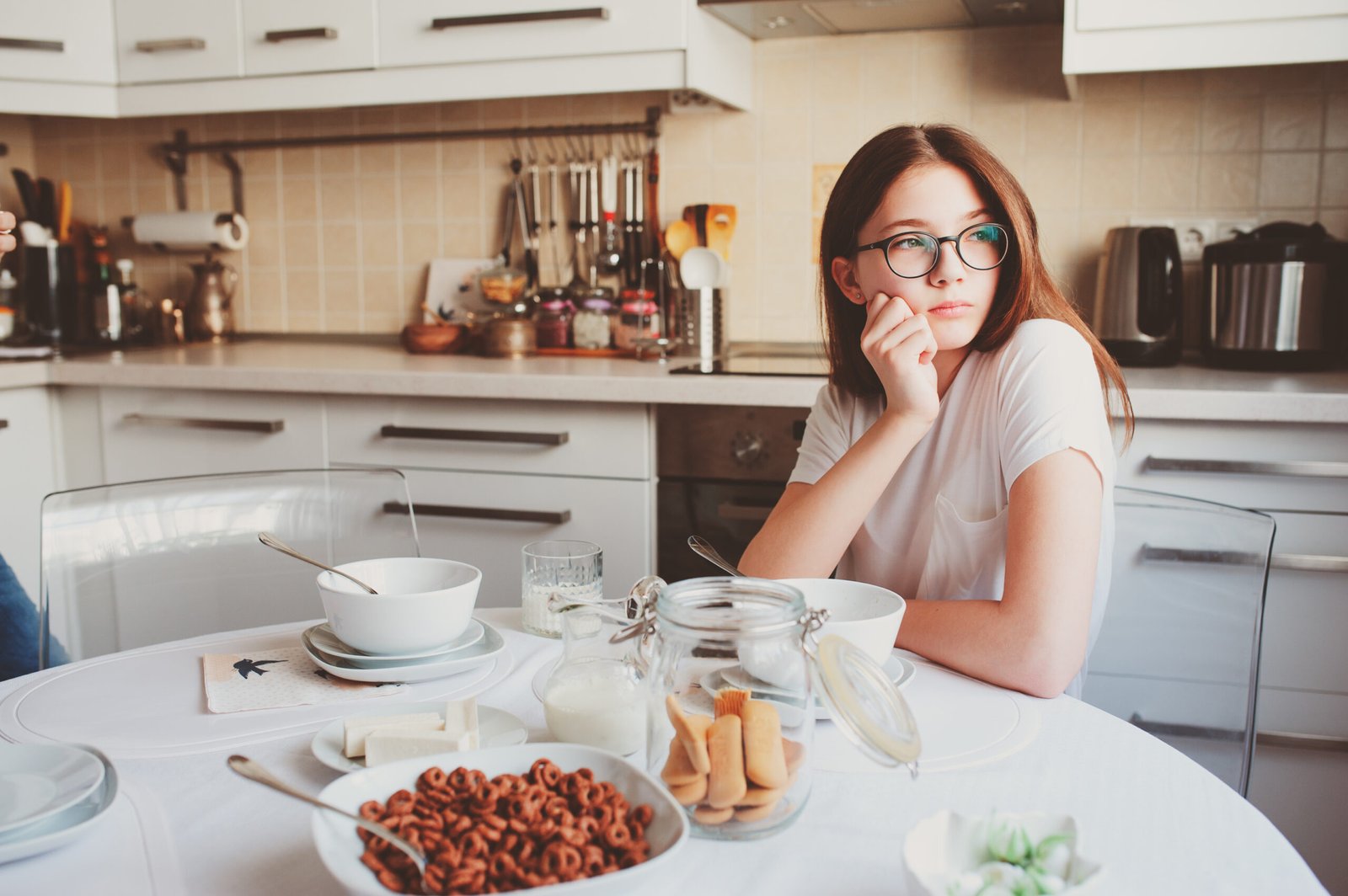 teen girl having breakfast at home in cozy modern kitchen