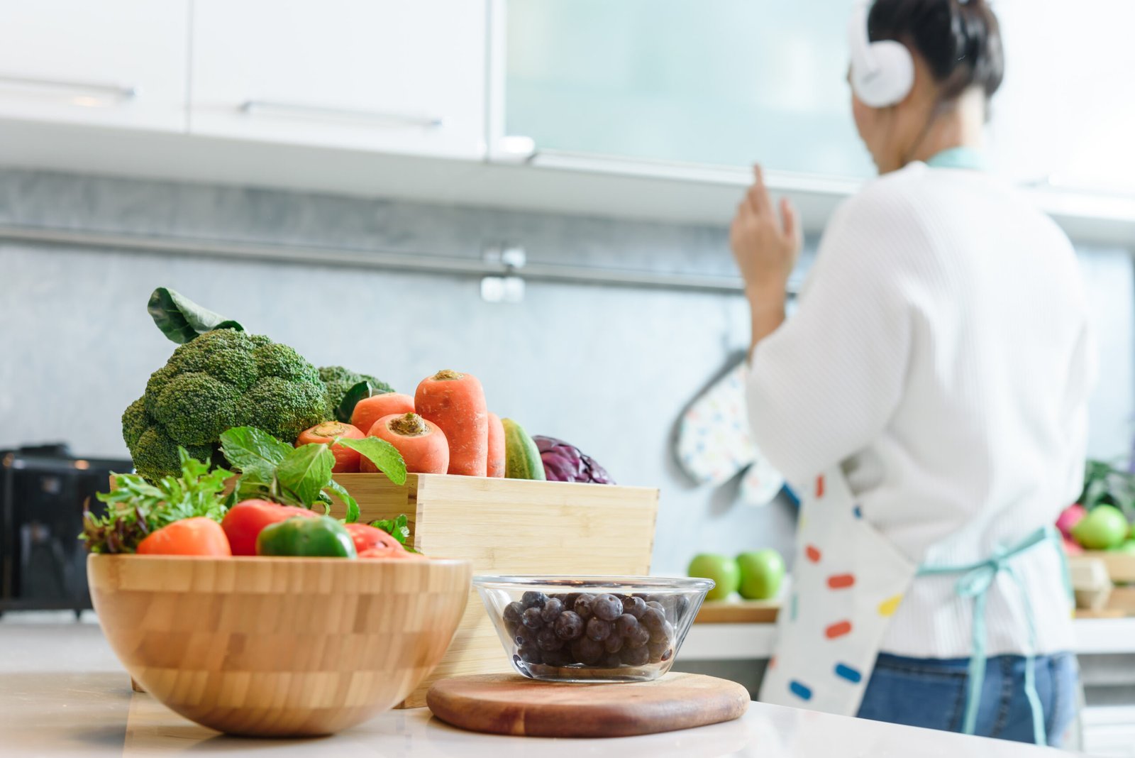 Woman in kitchen with various kind of vegetable and fruits that all are good for health and no meat, vegan lifestyle