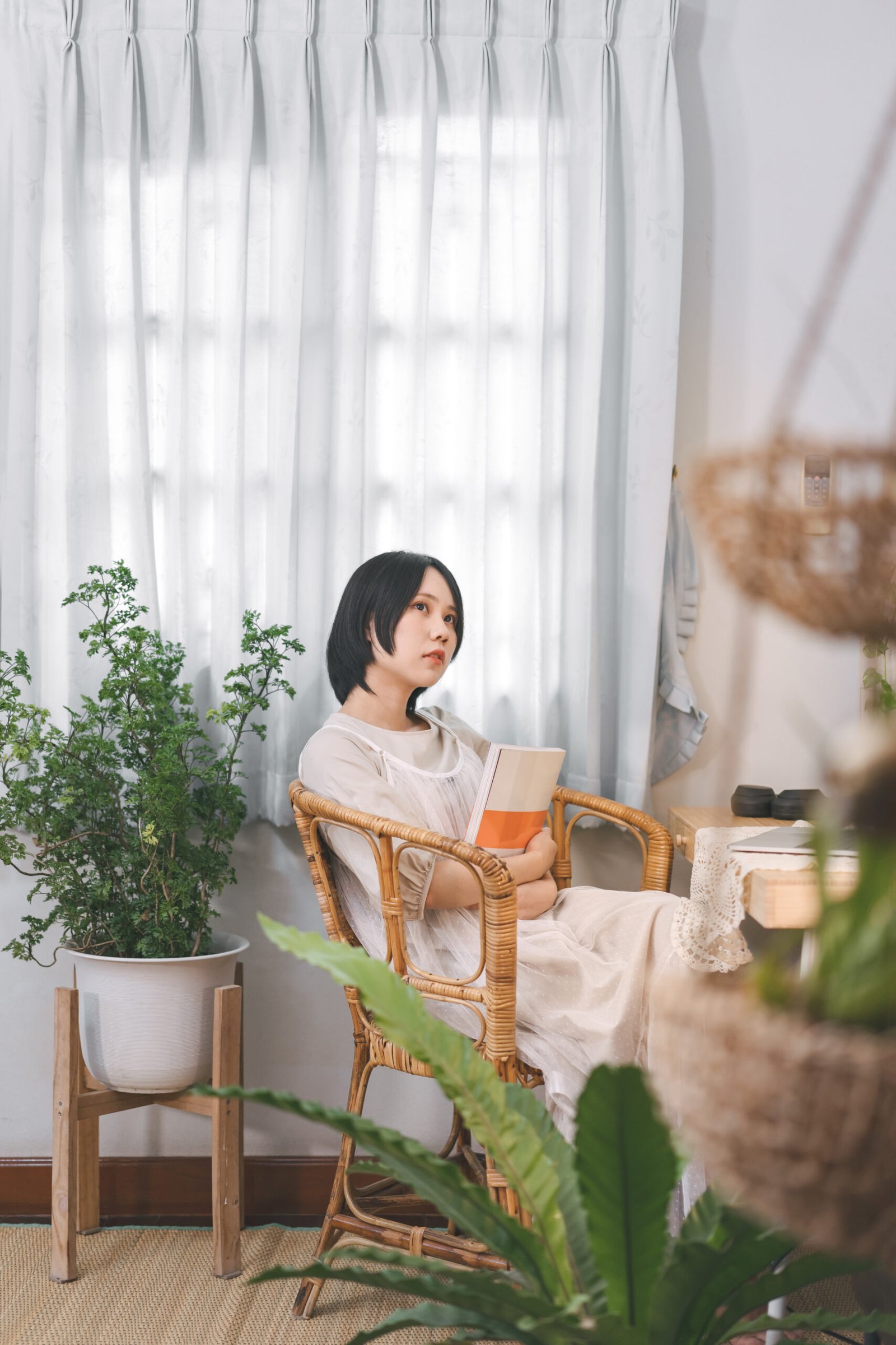 Asian woman reading a book in cozy room style with plant and lamp light living at home apartment youth culture style