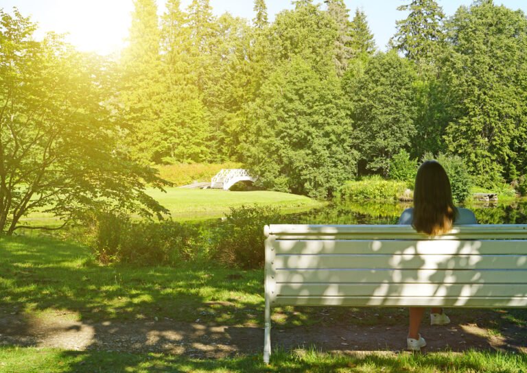 Woman sitting on the bench in the park at summertime.