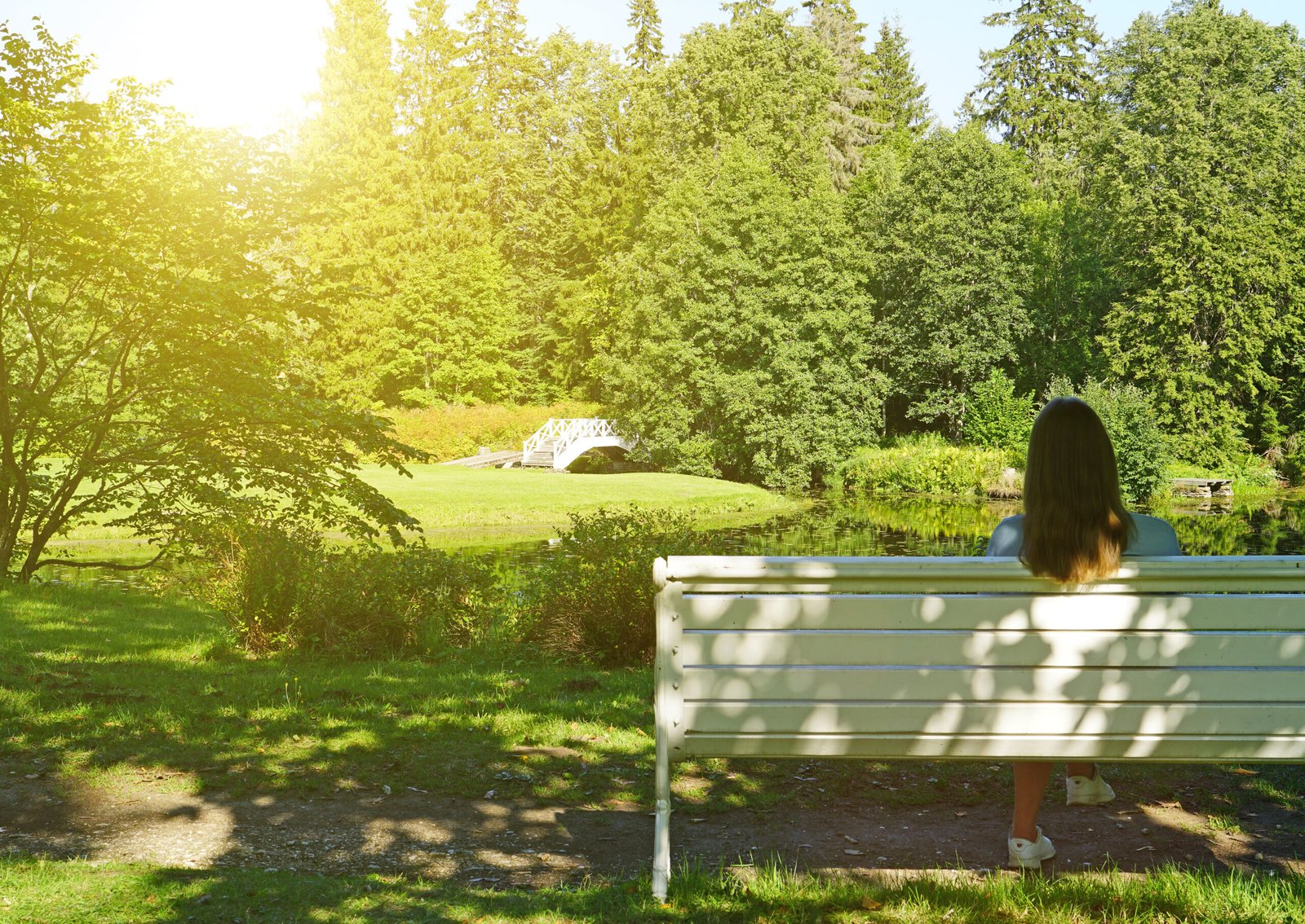 Woman sitting on the bench in the park at summertime.