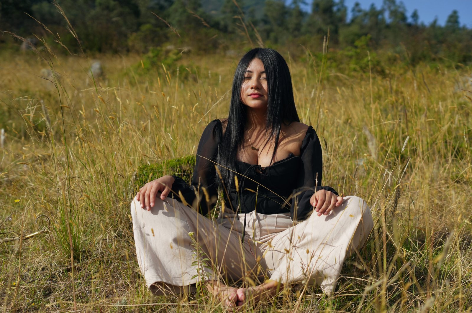Young woman meditating in a peaceful meadow with eyes closed