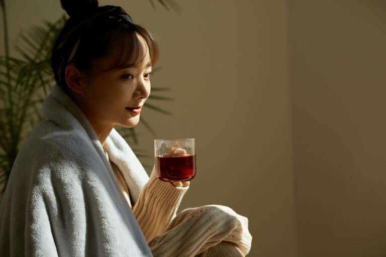 A young Asian woman relaxing at home drinking fruit tea