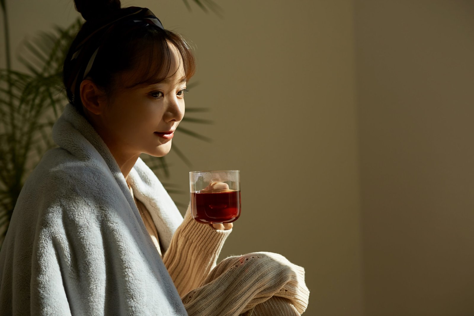 A young Asian woman relaxing at home drinking fruit tea