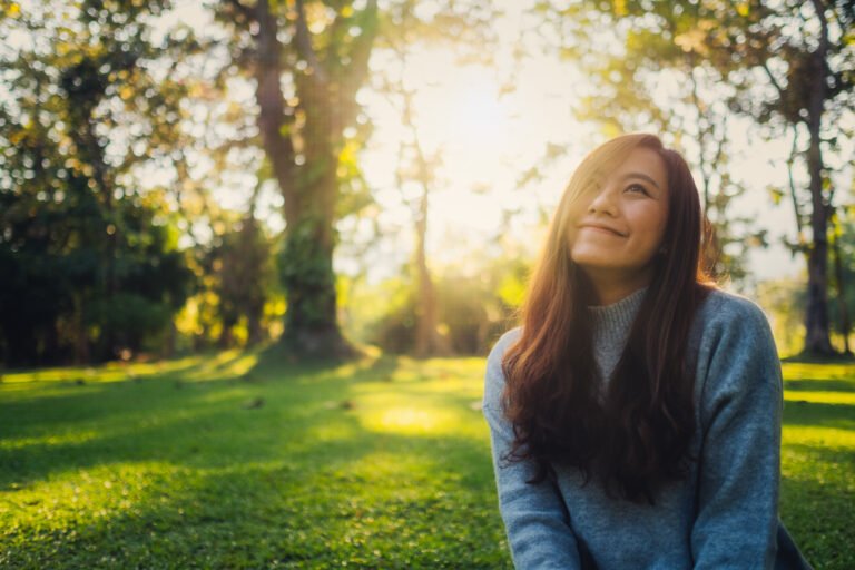 a beautiful asian woman sitting among nature in the park before sunset