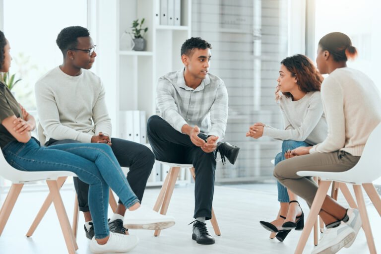 Shot of a diverse group of people sitting together and talking during therapy