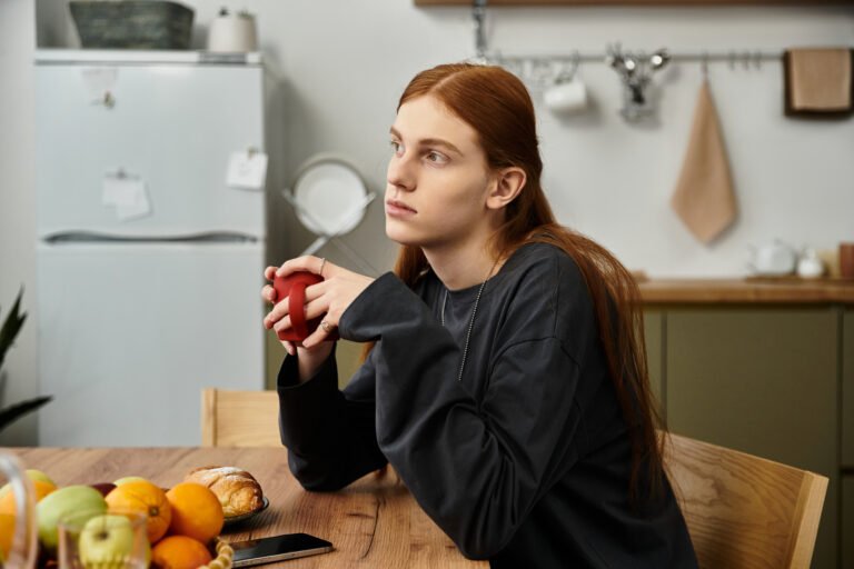 Young man enjoying a moment of reflection in a stylish apartment with fresh fruits
