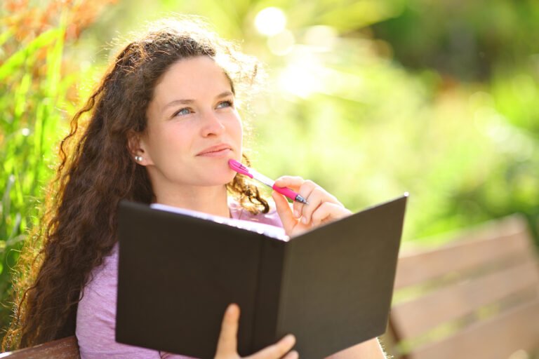 Woman writing and thinking in a park