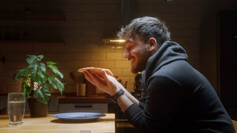 Man Eating Pizza Alone at Home in a Cozy Kitchen at Night