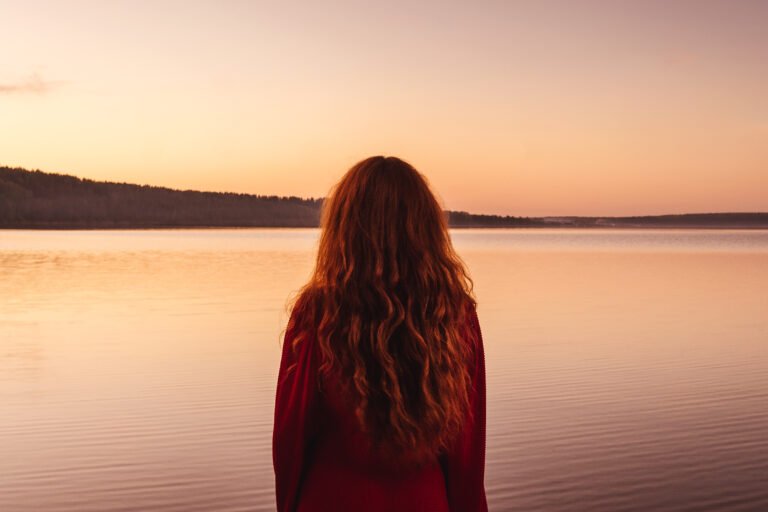 Red haired woman at sunset, back view.