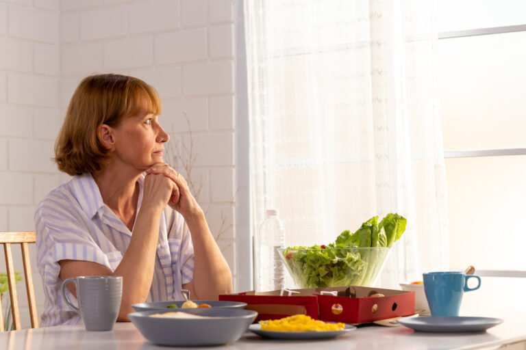 Lonely elderly retired grandmother stay at home and sitting alone on eating table in house, Missing her family and feeling unhappy concept