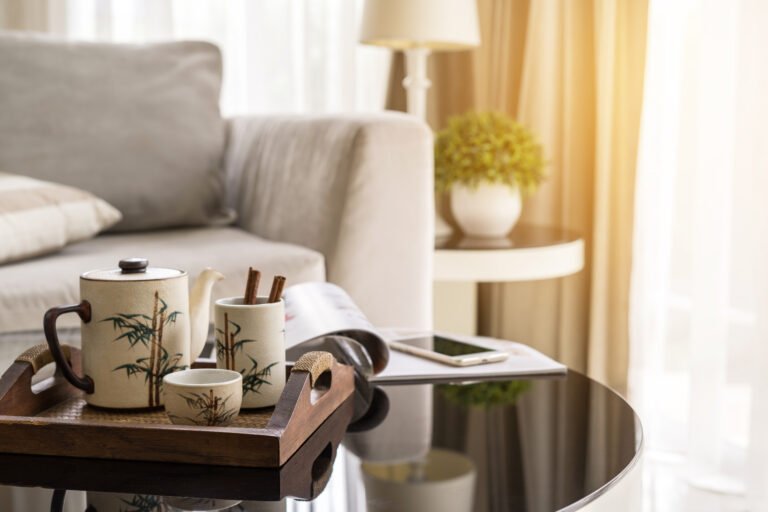 cup of tea on wooden tray on a round table with sofa in living room