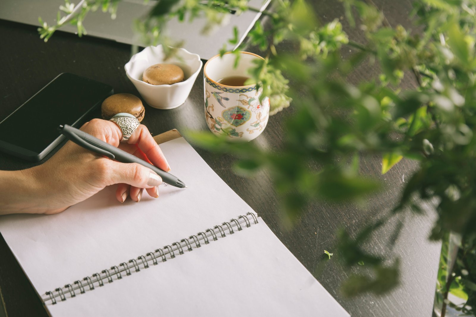 Woman hands writes a pen in a notebook, computer keyboard
